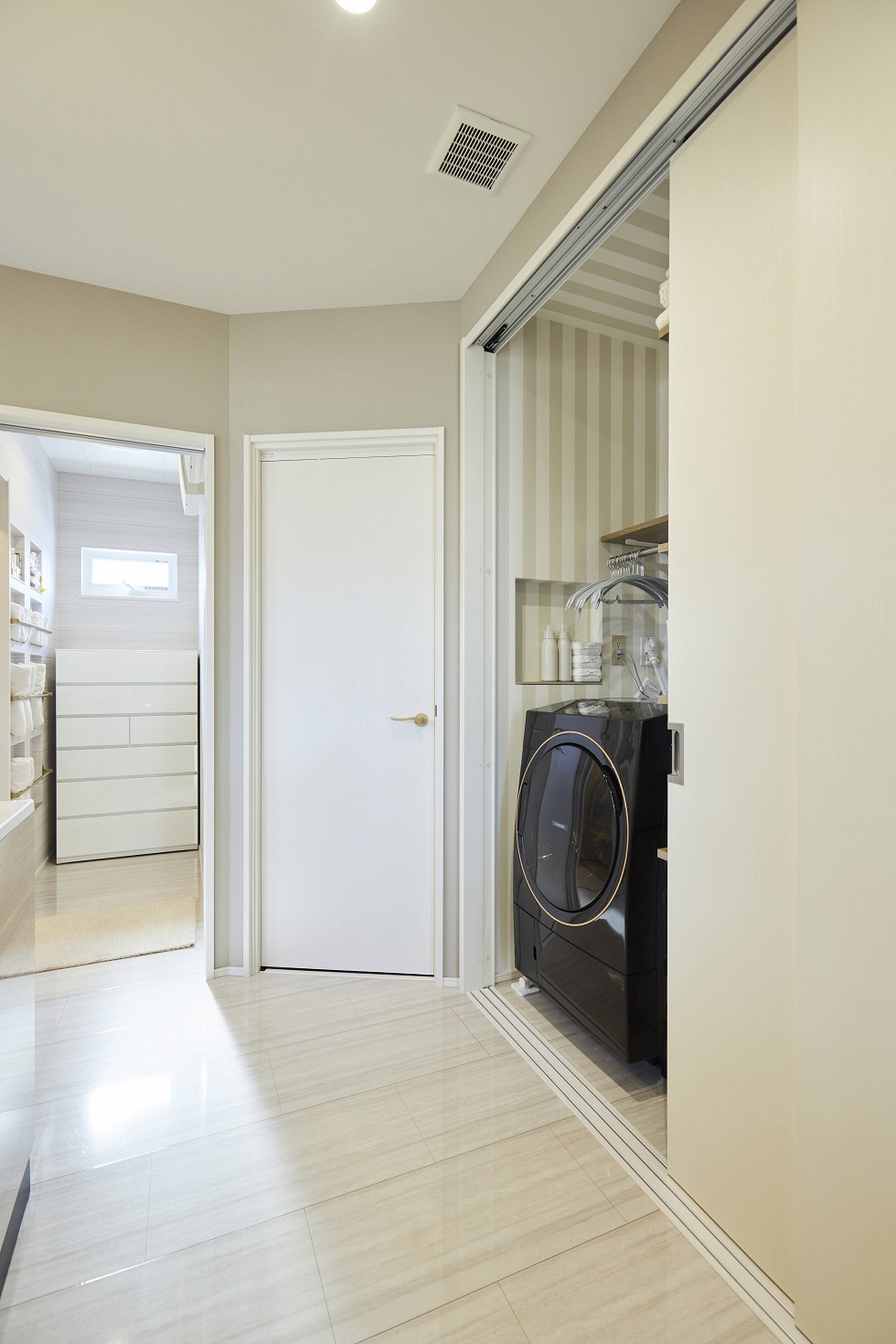 洗濯機はクローゼットと同じ扉の中にあるため、洗濯物の収納もスムーズです。また写真中央の扉はファミリークロークとなっており、身支度の移動が最短で完結できるこだわりの間取り。