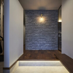 石積み壁とこだわりの照明が迎える、ホテルライクな玄関ホール