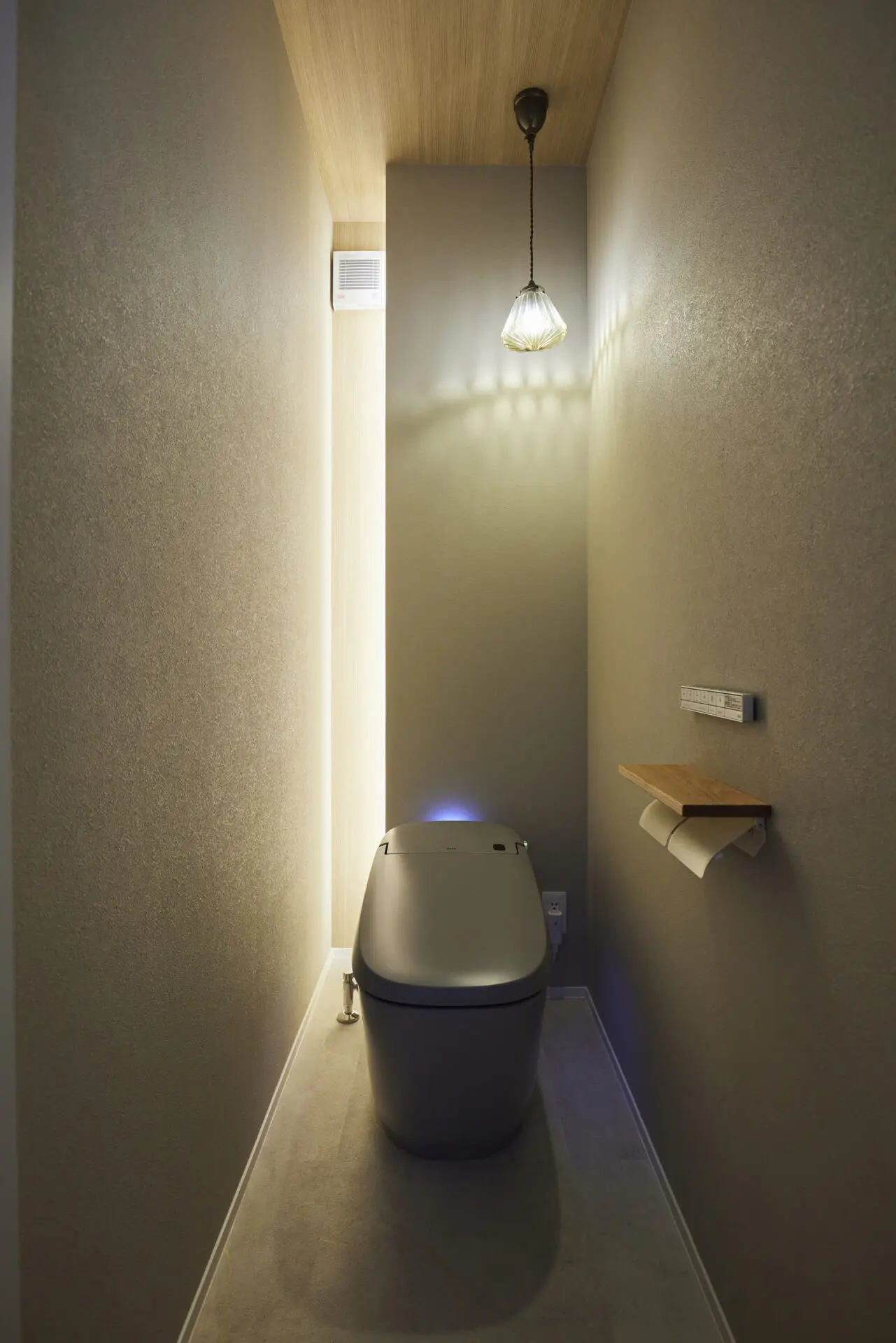 お家の中でも特に「お気に入り」と語ってくださったトイレ空間。奥の壁面を照らす縦ラインの間接照明と、デザインにこだわって選んだペンダントライトが、昼も夜も心地よい雰囲気を演出します。照明器具そのもののデザインもお気に入りのポイント。グレーカラーの便器をセレクトしたことで、スタイリッシュで落ち着きのある、ワンランク上のお手洗いに仕上がりました。