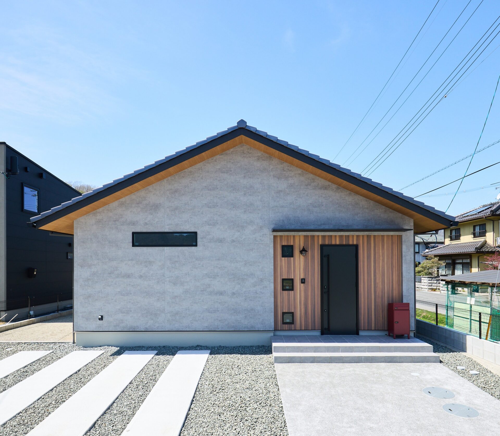 「他と被らない、シンプルさ」を追求した平屋の佇まいです。シャープな三角屋根のシルエットに、上品な風合いのグレーの外壁を採用。玄関まわりにあしらった縦格子の木目調サイディングと3連の窓が美しいアクセントとなり、シンプルながらも個性が光る洗練されたデザインに仕上がっています。