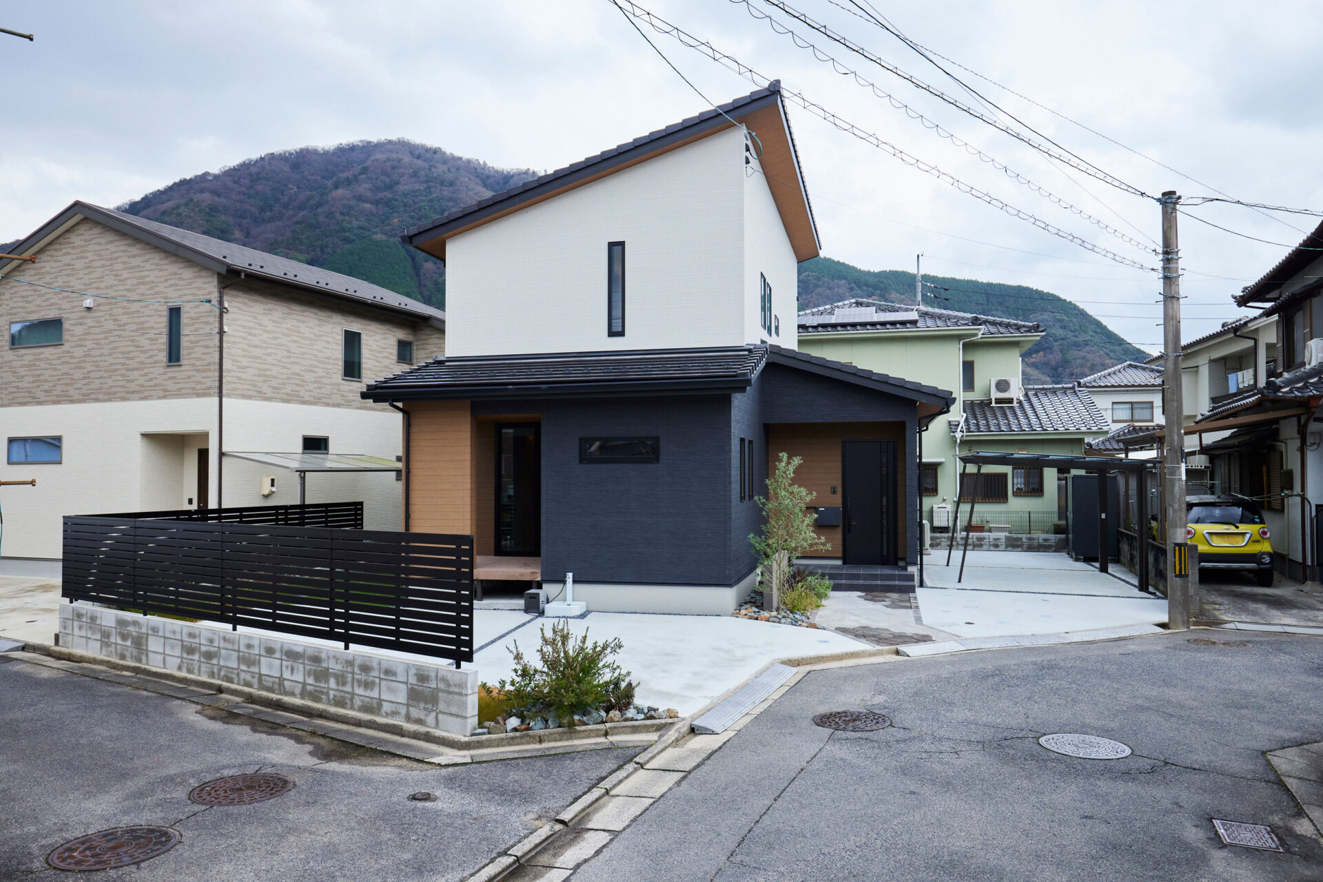 モノトーンの外観は片流れの屋根からちらりと見える軒天の木目がモダンな印象に。駐車場はお客様も駐車できるように4台分確保しました。